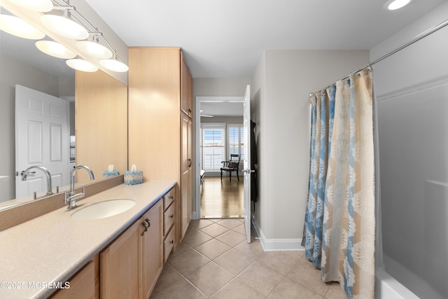 bathroom with a shower with shower curtain, vanity, baseboards, and tile patterned floors