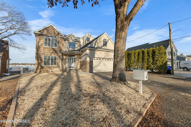 traditional-style home featuring driveway, stone siding, a garage, and fence