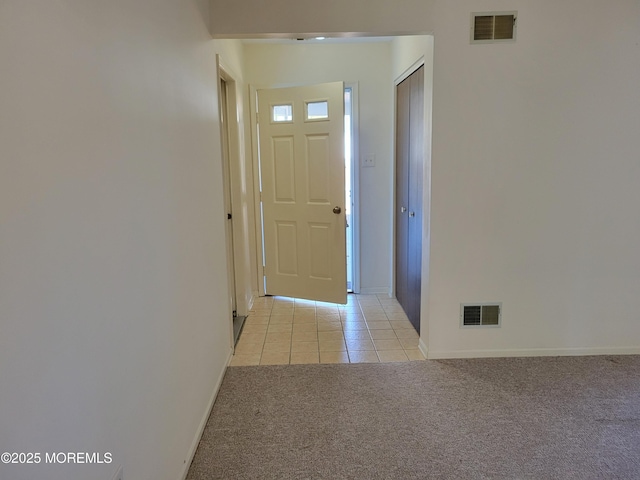 entryway featuring visible vents, light carpet, baseboards, and light tile patterned floors