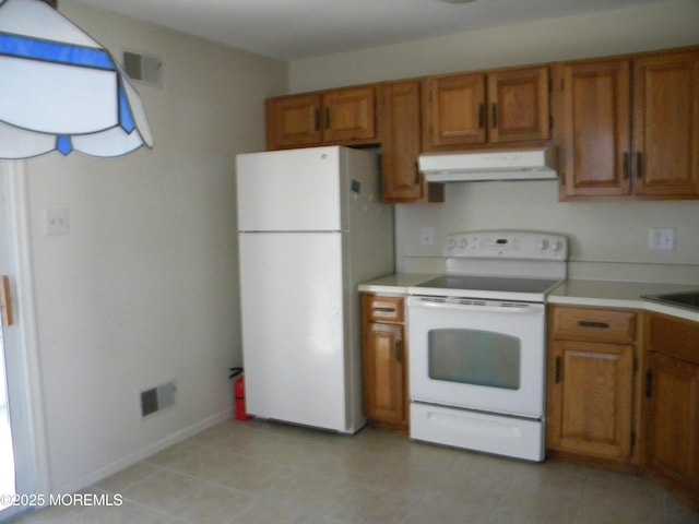 kitchen with white appliances, brown cabinetry, visible vents, and under cabinet range hood