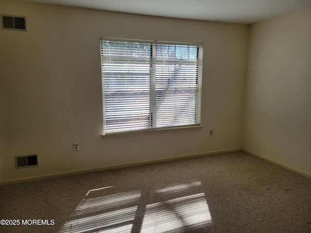 spare room with carpet floors, visible vents, and baseboards