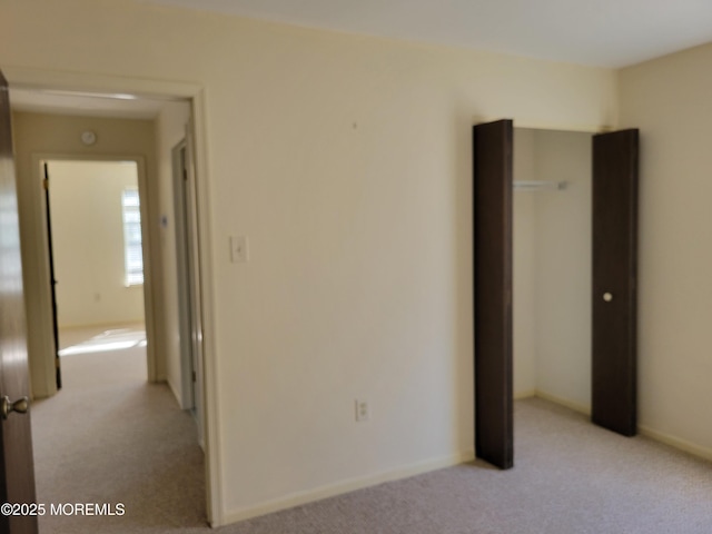 spare room featuring baseboards and light colored carpet