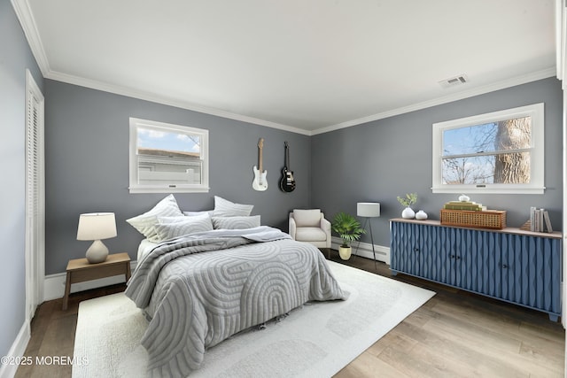 bedroom featuring multiple windows, wood finished floors, visible vents, and baseboards