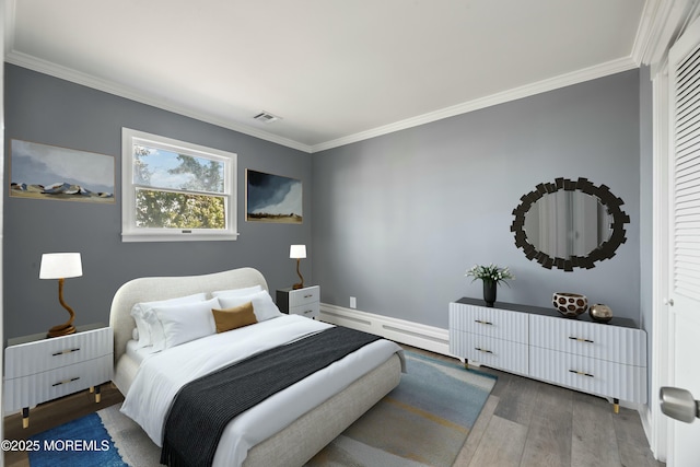 bedroom featuring baseboard heating, wood finished floors, visible vents, and crown molding