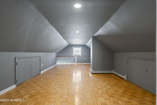 additional living space with a baseboard heating unit, vaulted ceiling, and baseboards