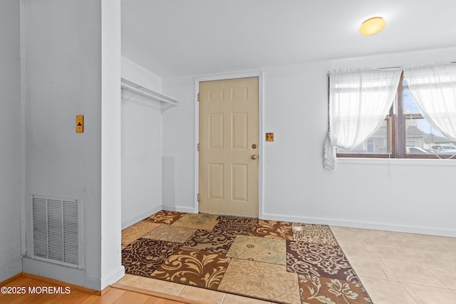 tiled entryway with baseboards and visible vents