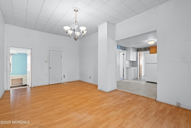 interior space featuring light wood-type flooring, a notable chandelier, and baseboards