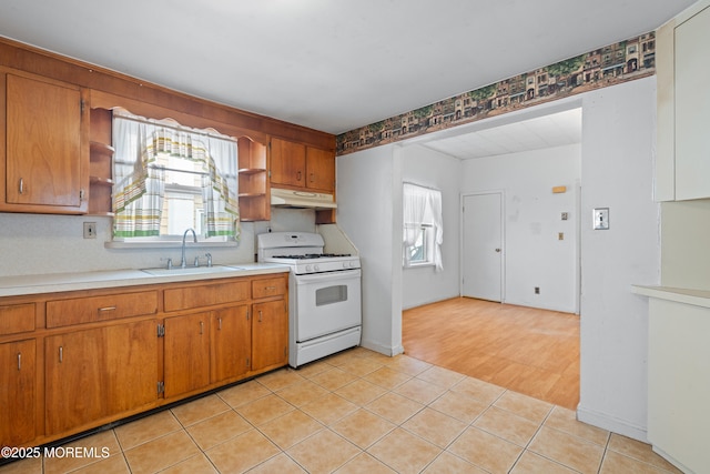 kitchen featuring gas range gas stove, open shelves, a sink, plenty of natural light, and under cabinet range hood