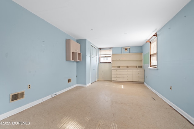 unfurnished room with light floors, visible vents, and baseboards