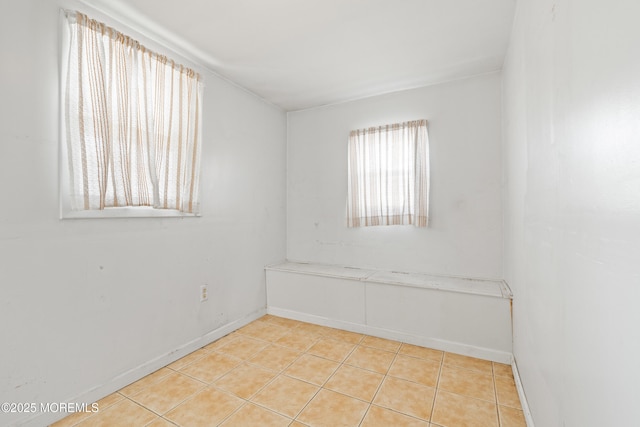 unfurnished room with light tile patterned floors and baseboards