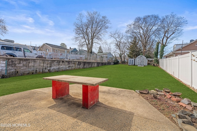 view of yard with an outbuilding, a fenced backyard, a patio, and a shed