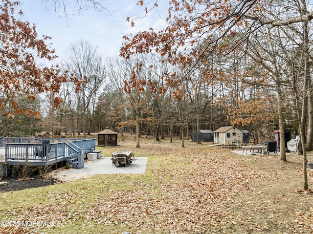 view of yard featuring a fire pit, an outdoor structure, a deck, and a gazebo