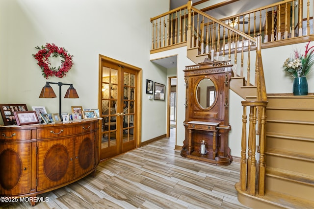 staircase featuring wood tiled floor, french doors, a high ceiling, and baseboards