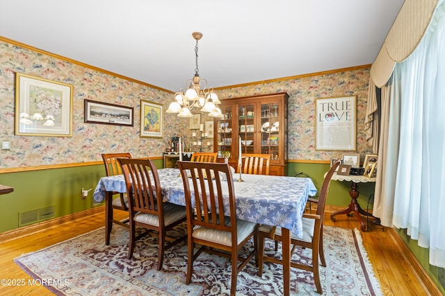 dining room with wainscoting, wood finished floors, visible vents, and wallpapered walls