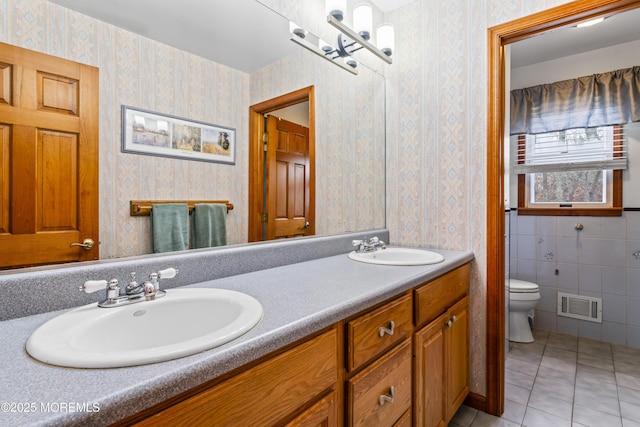 full bath with wallpapered walls, visible vents, and a sink