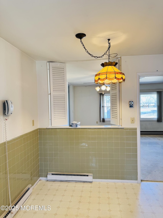 interior space featuring a wainscoted wall, a baseboard radiator, tile patterned floors, baseboard heating, and tile walls