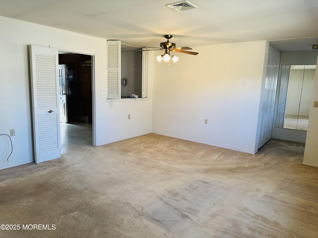 carpeted spare room featuring visible vents and ceiling fan