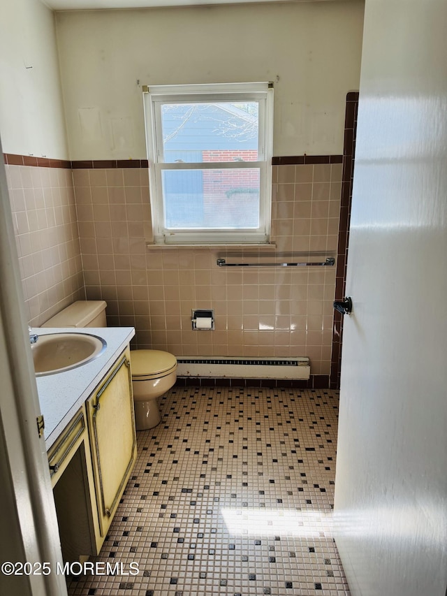 bathroom with toilet, vanity, tile walls, baseboard heating, and tile patterned floors