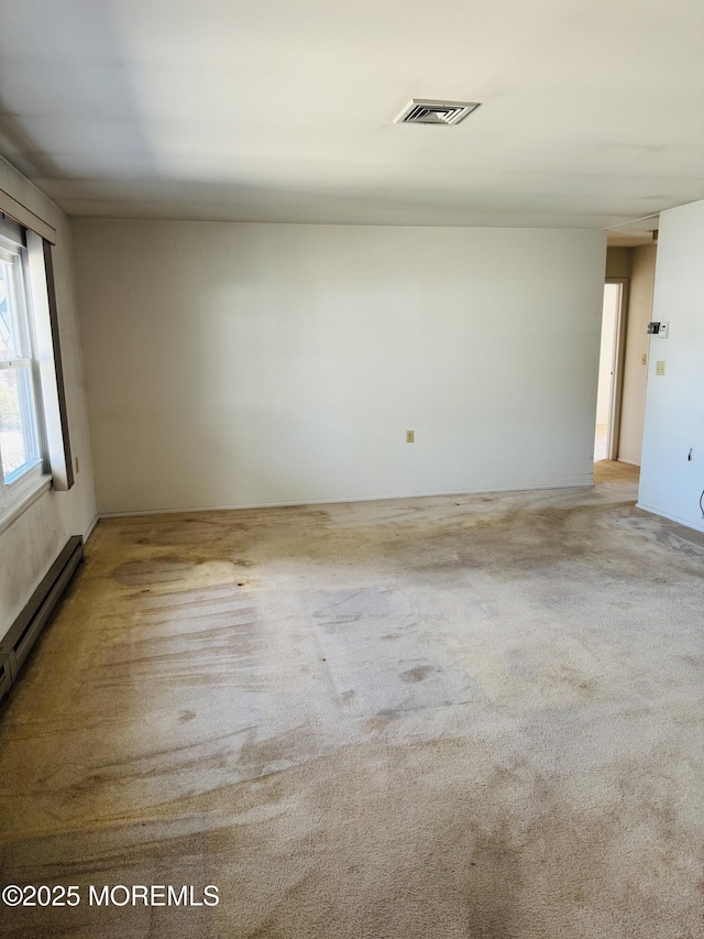 empty room with a baseboard heating unit, carpet, and visible vents