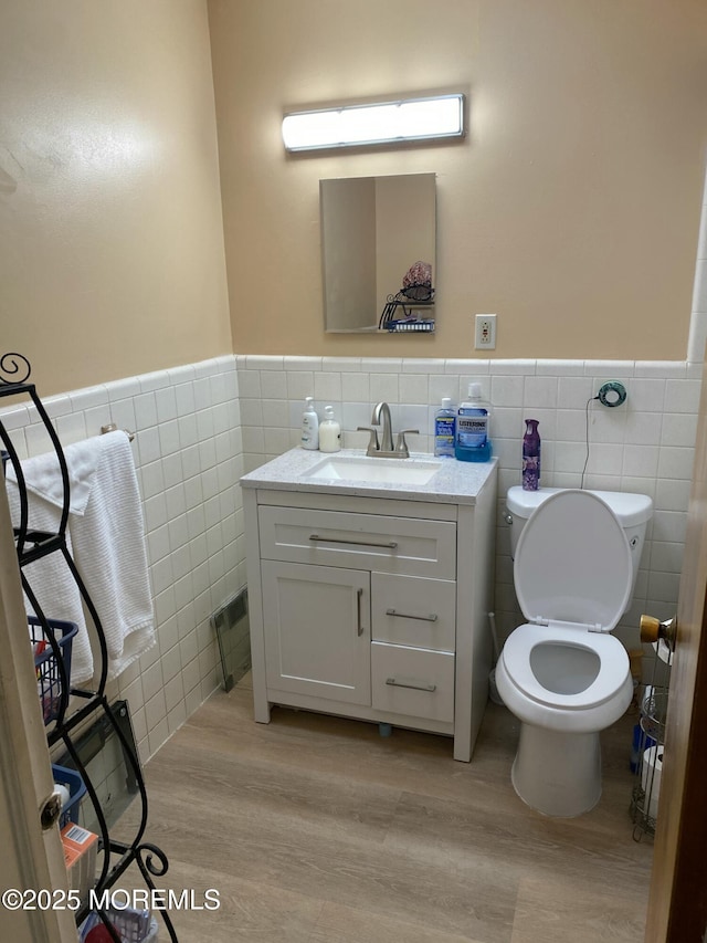 550 Wall St, Eatontown, NJ 07724 - half bath featuring tile walls, vanity, wainscoting, wood finished floors, and toilet