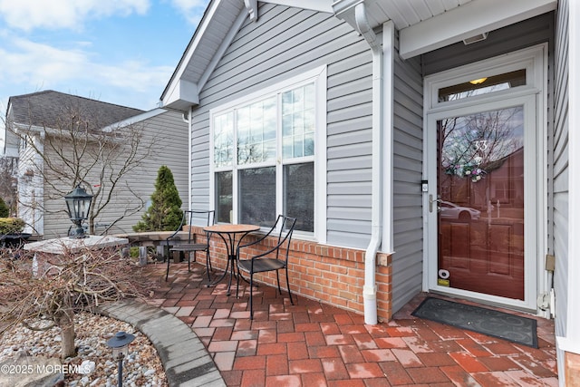 view of exterior entry with a patio and brick siding