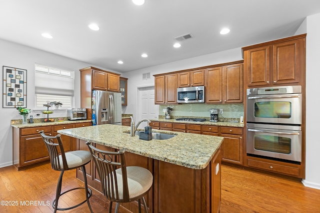 kitchen featuring light wood-style floors, visible vents, stainless steel appliances, and a sink