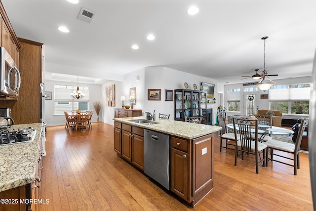 kitchen featuring a fireplace, visible vents, appliances with stainless steel finishes, light wood-style floors, and a sink