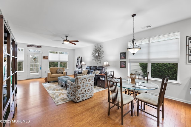 dining room with baseboards, light wood-style flooring, visible vents, and a ceiling fan