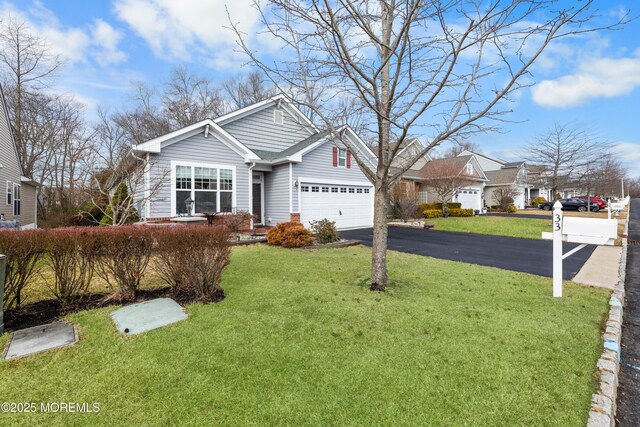 view of front of house featuring a garage, aphalt driveway, and a front lawn