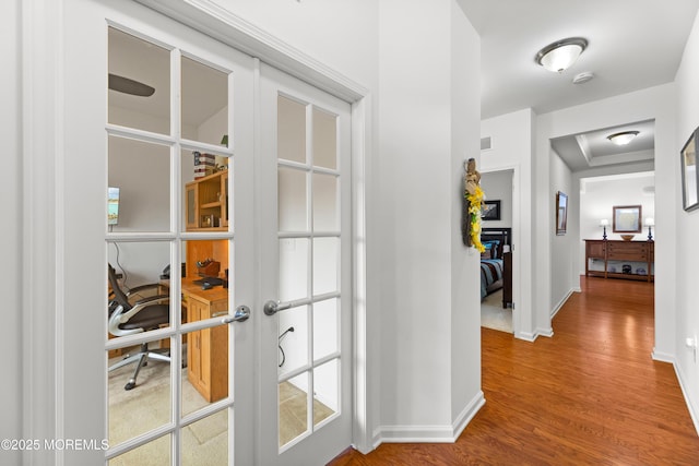 hall featuring french doors, visible vents, baseboards, and wood finished floors