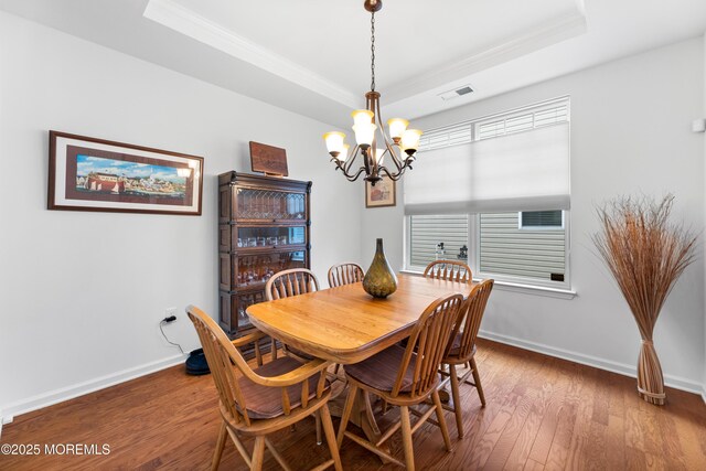 dining area featuring a raised ceiling, visible vents, ornamental molding, wood finished floors, and baseboards