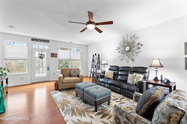 living room featuring light wood-style floors, baseboards, and a ceiling fan