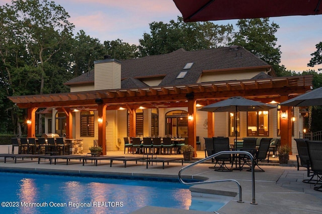 back of property with a pergola, a patio area, and an outdoor pool