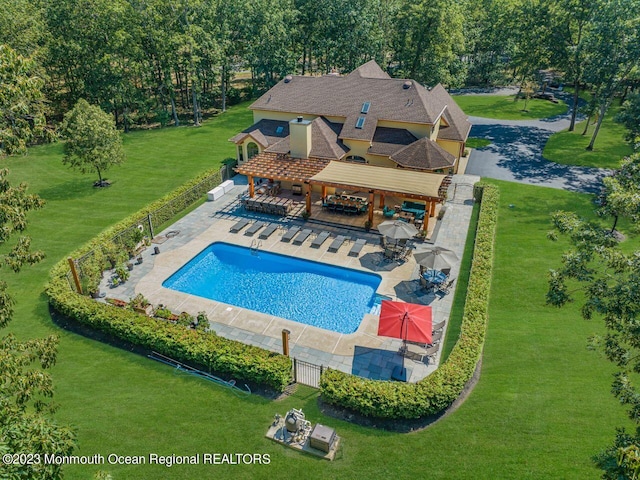 pool featuring a patio area, fence, and a lawn