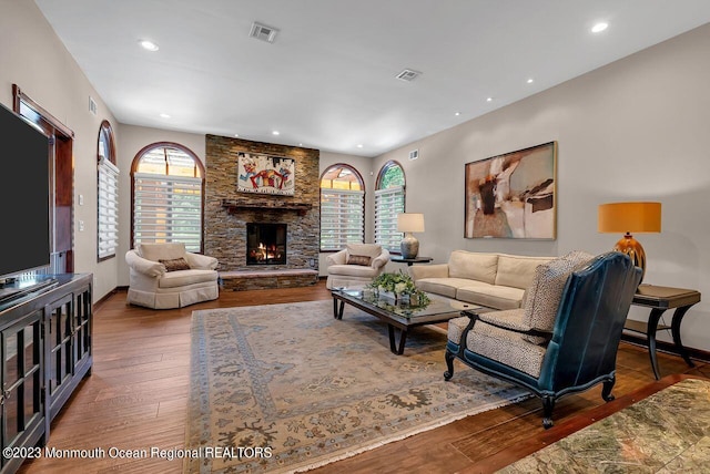 living area featuring visible vents, baseboards, wood-type flooring, a fireplace, and recessed lighting