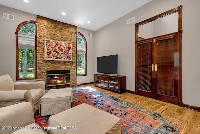 living room with visible vents, a fireplace, baseboards, and wood finished floors