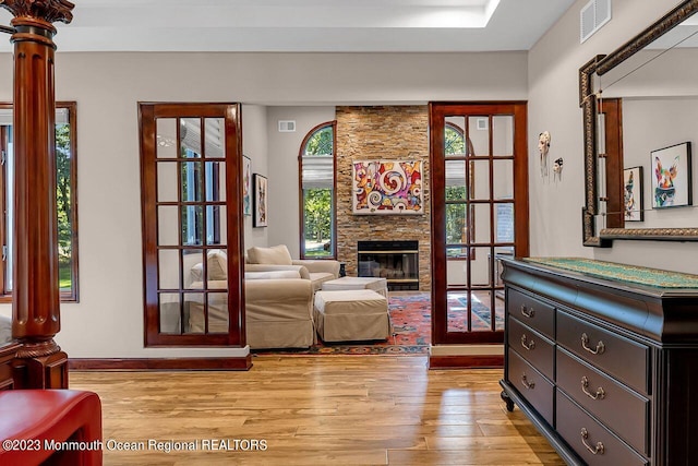 living area featuring light wood-style flooring, a fireplace, and visible vents