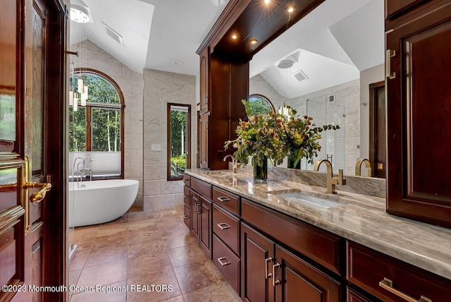 bathroom with lofted ceiling, a sink, and tile walls