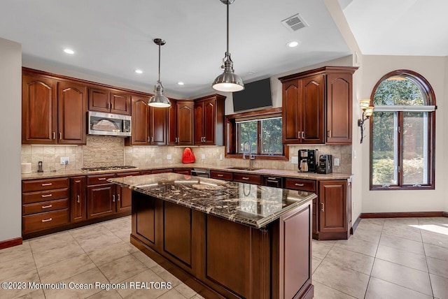 kitchen featuring light tile patterned floors, decorative backsplash, dark stone countertops, stainless steel appliances, and a sink