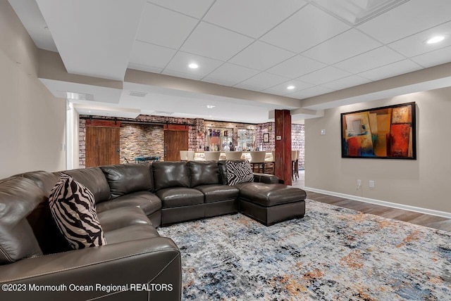 living area featuring a paneled ceiling, baseboards, wood finished floors, and recessed lighting