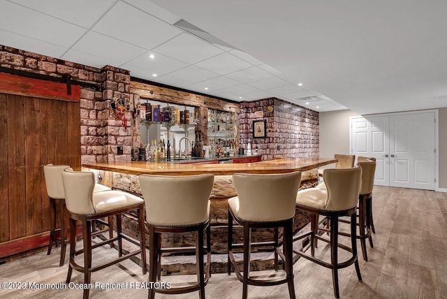 bar with a drop ceiling, indoor bar, and wood finished floors