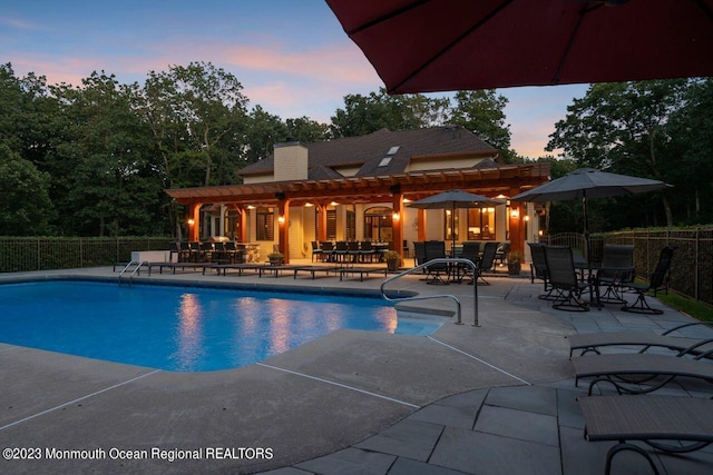 pool at dusk featuring a patio, fence, and a fenced in pool