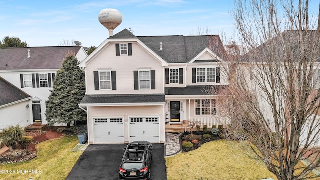 traditional-style home with aphalt driveway, a front lawn, a shingled roof, and an attached garage