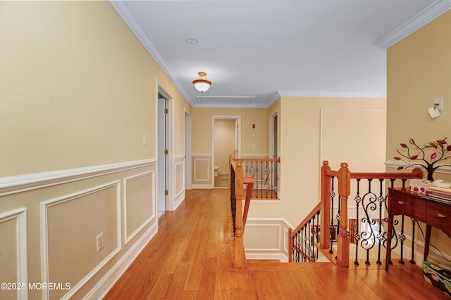 hallway with ornamental molding, a decorative wall, an upstairs landing, and wood finished floors