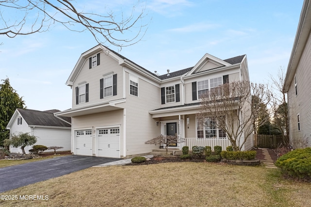 traditional-style home with a front lawn, covered porch, driveway, and an attached garage