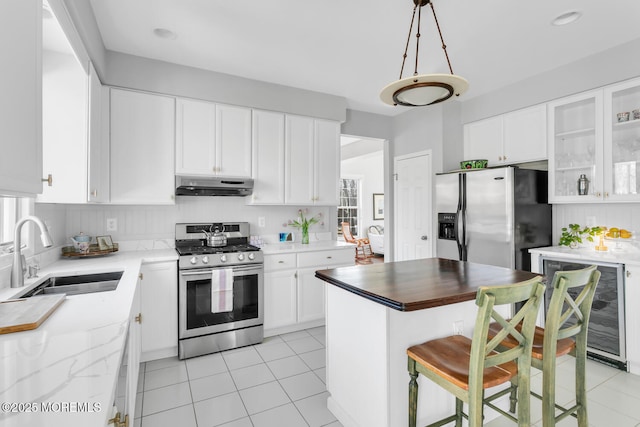 kitchen with wine cooler, appliances with stainless steel finishes, white cabinetry, a sink, and under cabinet range hood