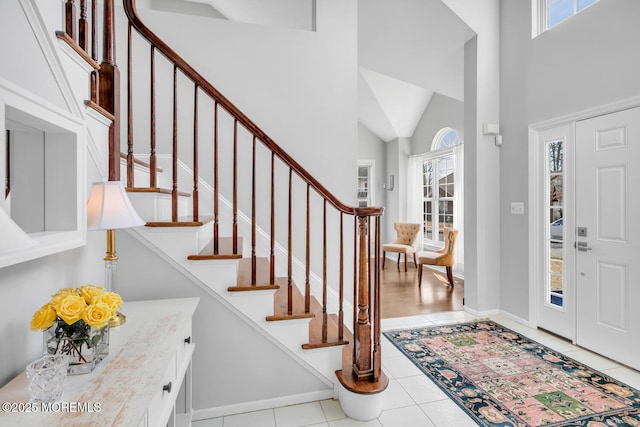 entryway featuring a healthy amount of sunlight, light tile patterned floors, a high ceiling, and baseboards