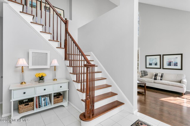 stairs featuring a towering ceiling, baseboards, and tile patterned floors