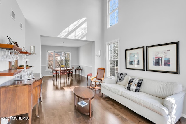 living room featuring dark wood-style flooring, a towering ceiling, and visible vents