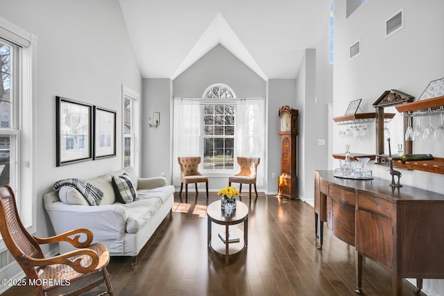 living room with dark wood-type flooring, visible vents, and a healthy amount of sunlight